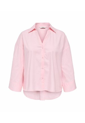 Chemise rose clair surdimensionnée avec boutons, manches longues larges et col pointu, présentant un ourlet asymétrique.