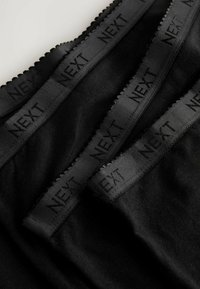 Juodas elastingas liemuo su iškilniu "NEXT" logotipu, turintis minkštą audinio kūną su lygiu paviršiumi ir banginėmis kraštinėmis.
