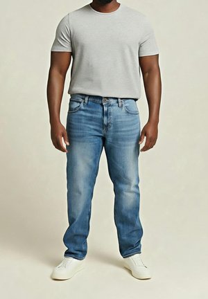 Mann trägt ein hellgraues T-Shirt mit kurzen Ärmeln, blaue Jeans mit geradem Schnitt und weiße Turnschuhe, steht vor einem einfarbigen beigen Hintergrund.