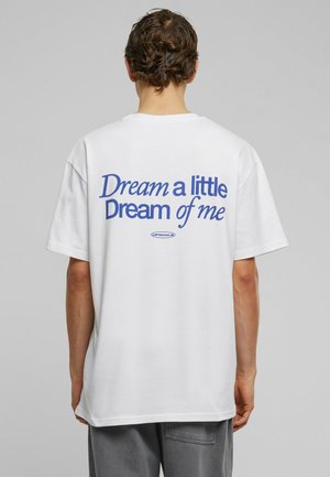 T-shirt en coton blanc, coupe décontractée, avec un texte graphique bleu au dos : "Rêve un peu de moi." Manches courtes, col rond.