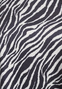 Látka se zebra vzorem, která se vyznačuje výraznými černobílými pruhy s texturovanými vlnami, což vytváří dynamický vizuální efekt.