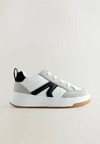 Balti odiniai sportbačiai su pilkais zomšos akcentais ir juodomis juostelėmis. Yra plokščia gumos padais ir penki akių skylės su baltais raišteliais.