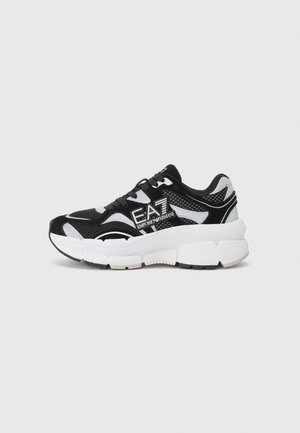 Black and white athletic shoes with a mesh upper, textured details, chunky white sole, and prominent EA7 branding on the side.