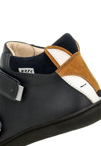 Scarpa in pelle nera con dettagli in suede marrone e blu navy. Presenta un design di volpe sul tacco e una fascia in velcro per la chiusura.