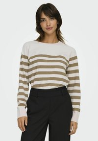 Pull rayé clair avec des rayures horizontales beige et blanches, encolure ronde et manches longues, associé à un pantalon noir taille haute.