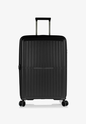 Valigia nera rigida con scanalature verticali, manico metallico estraibile, quattro ruote e logo del marchio sulla parte frontale.