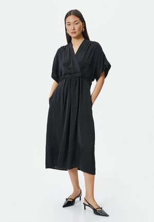 Black wrap dress made of lightweight material with wide short sleeves and a tied waist detail, featuring two side pockets and a flowy silhouette.