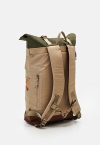Zaino beige a rotolo con dettagli verdi, spallacci imbottiti, una tasca con zip laterale e particolari in pelle alla base anteriore.