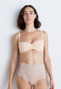 Μπεζ σουτιέν με στηρίγματα, με λεία ύφανση, φαρδιές τιράντες και ελαφριά επένδυση, συνδυασμένο με μπεζ κιλοτάκι ψηλής μέσης με δαντέλα.