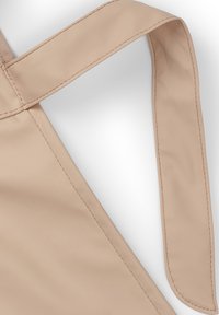 Beige tygväska med en slät yta, försedd med en lång, platt rem, ordentligt sydda kanter och en något glansig yta.