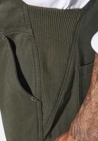 Olivgrüne Cargo-Hosen verfügen über einen gerippten Bund, seitliche Taschen mit Druckknopfverschluss und ein seitliches Taschendesign für Funktionalität.