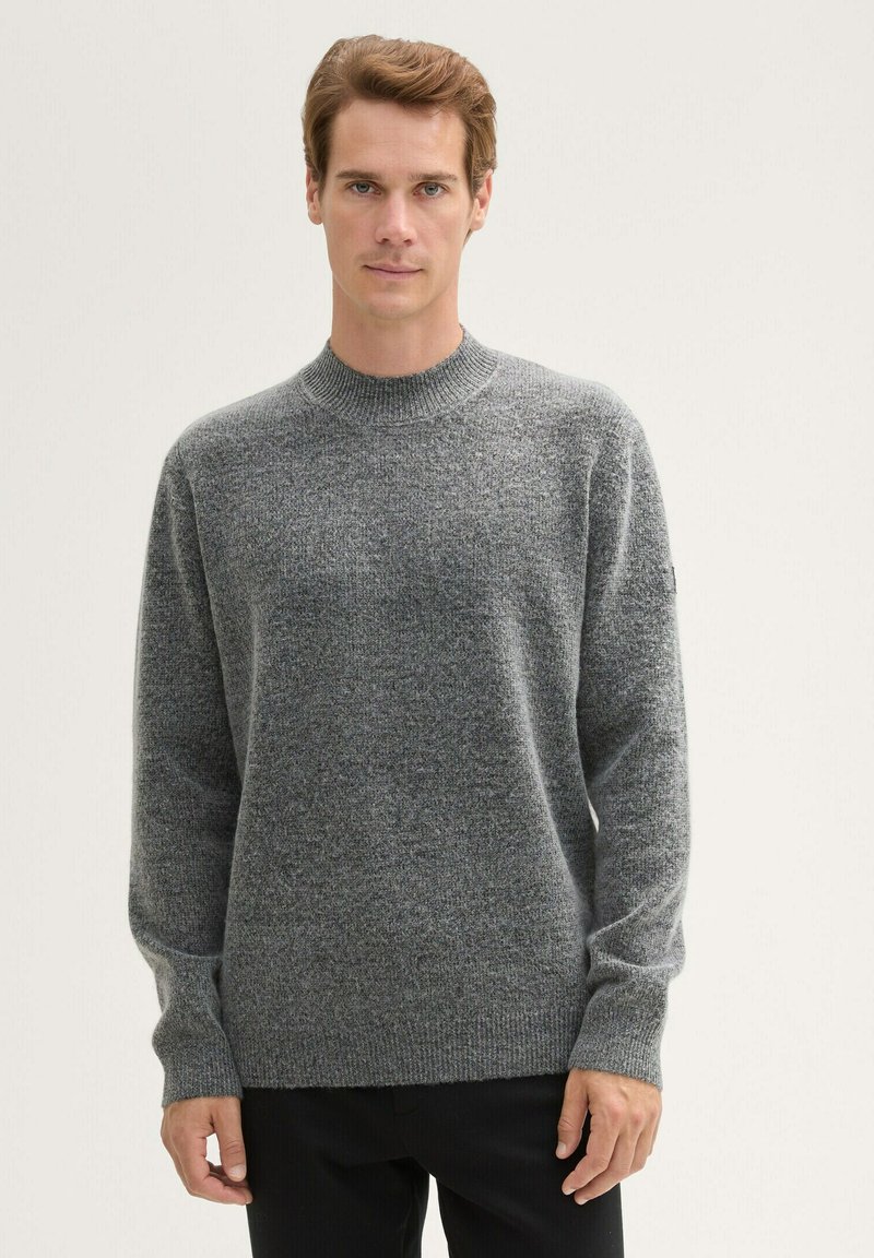 Grauer Strickpullover mit hohem Kragen, langen Ärmeln und einem strukturierten Stoff. Mit gerippten Bündchen und Saum.