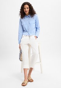 Blau-weiße gestreifte Button-Up-Bluse mit zwei Brusttaschen, weiße Leinenhose und braune Sandalen. Einfaches Design, entspannte Passform.