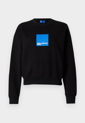 Schwarzer Sweatshirt mit einem kurvenförmigen Design, das ein blauen Quadratlappenlogo enthält, auf dem "KARL LAGERFELD JEANS" steht. Hergestellt aus einer weichen Baumwollmischung.