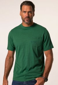 Camiseta verde de manga corta hecha de tejido suave, con un bolsillo en el pecho con texto en relieve, cuello redondo y un ajuste relajado.