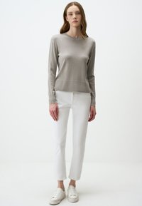 Pull à manches longues gris clair avec un col rond et des poignets côtelés, associé à un pantalon droit blanc et des baskets blanches.