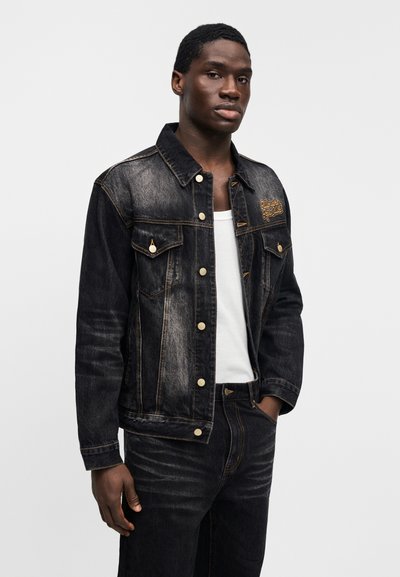 Τζιν μπουφάν σε σκούρο μπλε με ξεθωριασμένο φινίρισμα. Διαθέτει διπλές τσέπες στο στήθος, χρυσά μεταλλικά εξαρτήματα και κεντημένο λογότυπο στο στήθος.