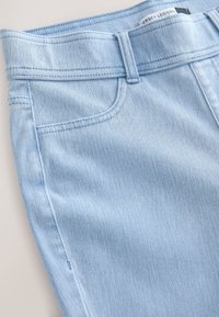 Svetlo modre legice iz jeansa z gladko teksturo, dizajnom s petimi žepi in subtilnimi detajli šivov. Elastičen pas za udobje.