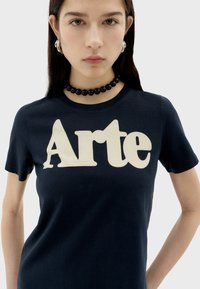 T-shirt en coton bleu marine à manches courtes, avec un grand imprimé crème du mot "Arte" à l'avant et un col rond classique.