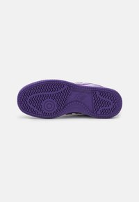 Sneaker viola con una suola in gomma testurizzata, caratterizzata da un motivo a zigzag. Dettaglio del logo in rilievo sulla suola intermedia.