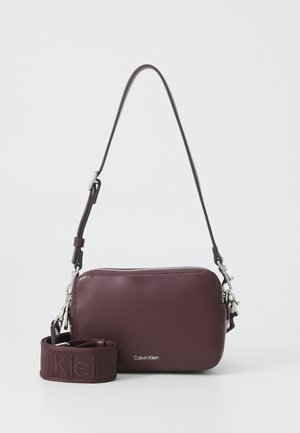 Bordeaux leren schoudertas met zilverkleurige hardware, ritssluiting en verstelbare strap met het 'Calvin Klein' logo in reliëf op de voorkant.