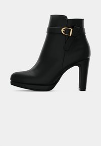 Μαύρη δερμάτινη μπότες ζιβάγκο με μυτερή μύτη, ψηλή γόβα και χρυσή μεταλλική αγκράφα στο πλάι. Λείος υφασμάτινος χαρακτήρας με ελάχιστη διακόσμηση.