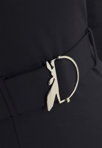 Schwarzer Stoffgürtel mit einer silberfarbenen runden Schnalle, die ein markantes, eckiges Auschnittdesign aufweist. Glatte Textur mit nahtlosem Finish.
