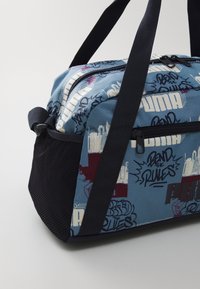 Kék és fekete sporttáska tartós szövetből készült. Absztrakt grafikus mintázattal, dupla füllel és cipzáras zárással rendelkezik. Hálós oldalsó panel.