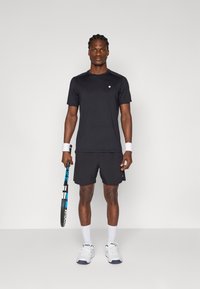 Black athletic t-shirt with short sleeves and a round neckline, paired with black shorts. White wristbands and tennis racket with blue accents.