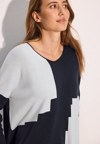Pullover mit einem navyblauen und hellgrauen abstrakten Blockmuster, aus weichem Stoff gefertigt. Features einen runden Halsausschnitt und eine lässige Passform.