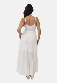 Witte maxi jurk met een gesmokt lijfje, verstelbare schouderbanden en een gelaagde rok met uitsnijdingen. Glad stoftextuur.