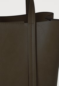 Borsa tote in eco-pelle marrone con superficie texturizzata, cuciture a vista e due manici robusti. Design minimalista senza decorazioni.