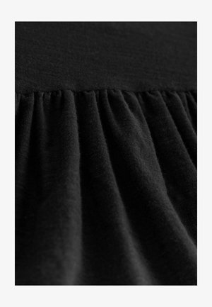 Tela negra con una superficie texturizada con pliegues recogidos, que muestra suavidad y un color oscuro uniforme en toda su extensión.