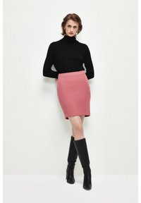 Zwarte coltrui gecombineerd met een aansluitende roze rok. Het model draagt kniehoge zwarte haklaarzen. Vlotte texturen en eenvoudig ontwerp.