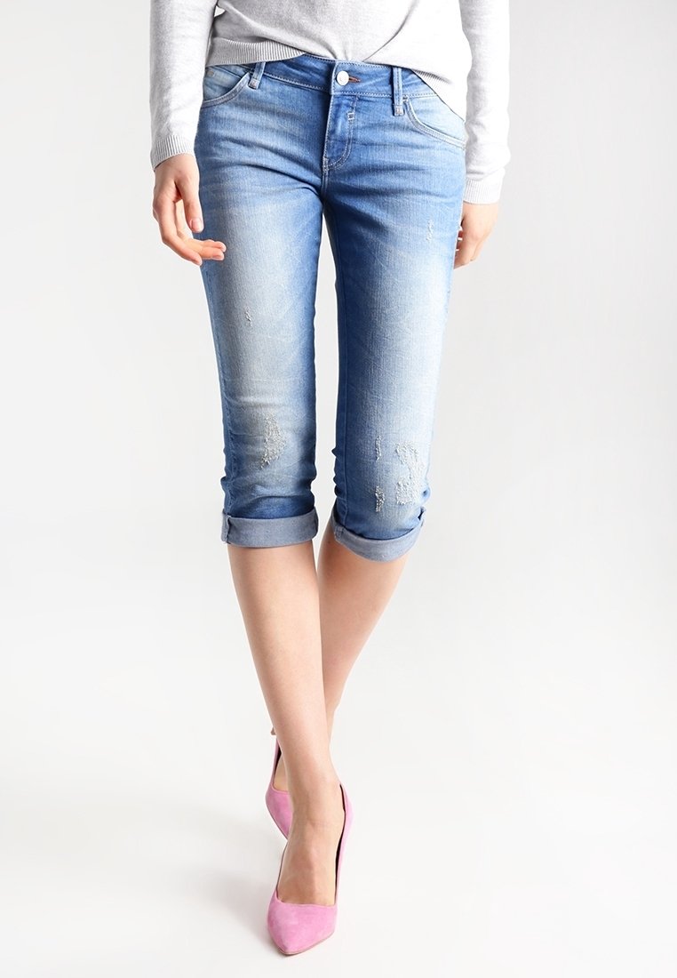 Světle modré denimové capri džíny s mírně poškozeným designem, ohrnutými manžetami, pěti kapsami, opotřebovaným vzhledem a přiléhavým střihem.