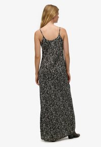 Maxikjole i sort med blomsterprint, lavet af letvægtsstof; har tynde stropper og en flydende silhuet, der når til midt på læggen.