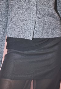 Hall toode, mis on hall soonikuga kootud kardigan, millel on nööbivarrukad, on kihilise musta siidise seeliku peal, millel on voolav disain.