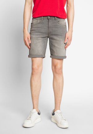 Graue Jeansshorts mit ausgewaschenem Look, umgekrempelten Säumen, Taschen vorne und hinten, kombiniert mit weißen Sneakern und einem roten T-Shirt.