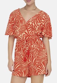 Rompers court rouge et crème avec un motif de feuilles, décolleté en V, manches courtes, taille à cordon et accents en franges. Fabriqué en tissu léger.