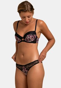 Soutien-gorge noir à bordure en dentelle avec des bonnets à motif floral et un string transparent assorti. Il dispose de bretelles ajustables et d'un design découpé sur le soutien-gorge.