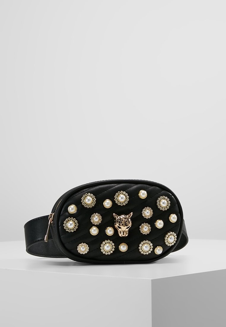 Borsa a tracolla ovale in pelle nera con testa di leopardo in oro, decorazioni in perle e strass, e chiusura con zip su sfondo neutro.