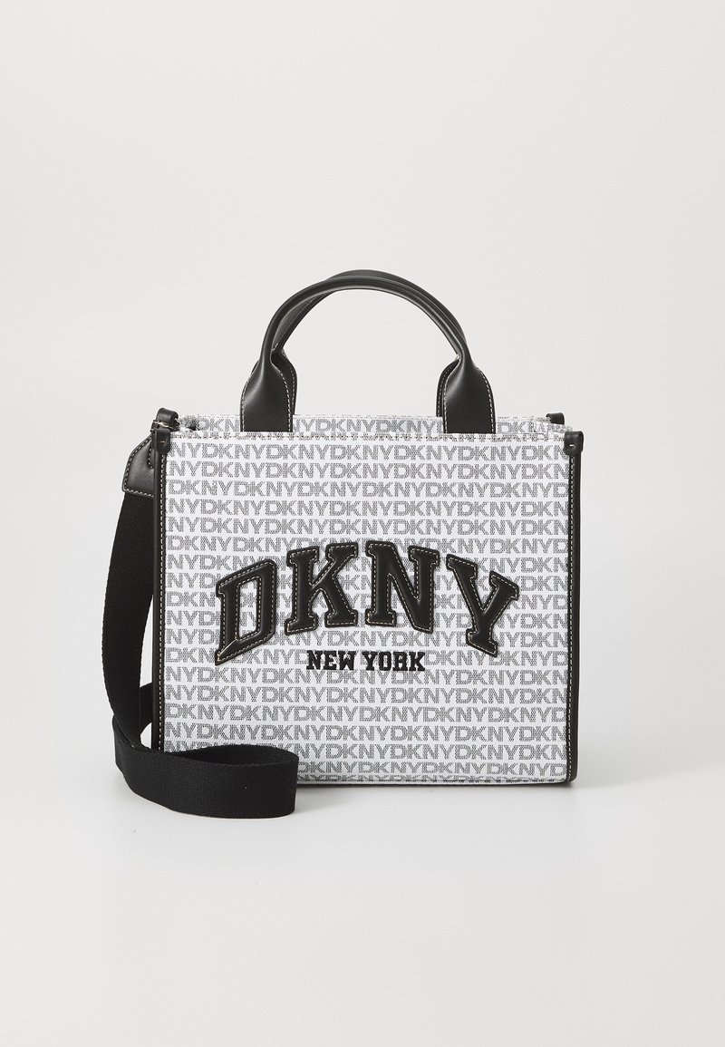 Bolsa branca com o logo "DKNY" em preto, apresentando um padrão repetido. Detalhes em material preto, alças curtas e uma alça de ombro destacável.
