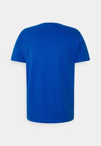 T-shirt bleu roi uni à manches courtes avec col rond, vu de dos sur un fond gris neutre.