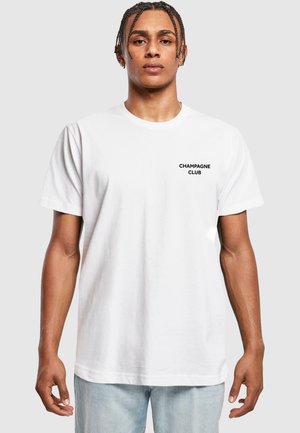 White cotton t-shirt featuring a small black "CHAMPAGNE CLUB" logo on the left chest, relaxed fit, and short sleeves.