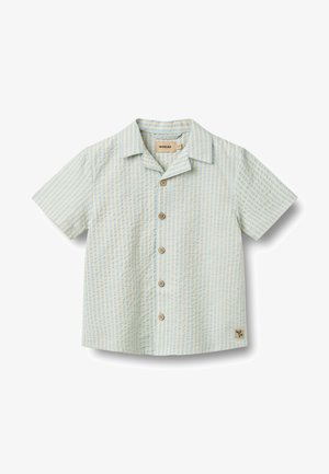 Camisa de manga corta con botones en azul claro y rayas verticales blancas. Presenta botones de madera y un pequeño parche con el logo en el dobladillo.