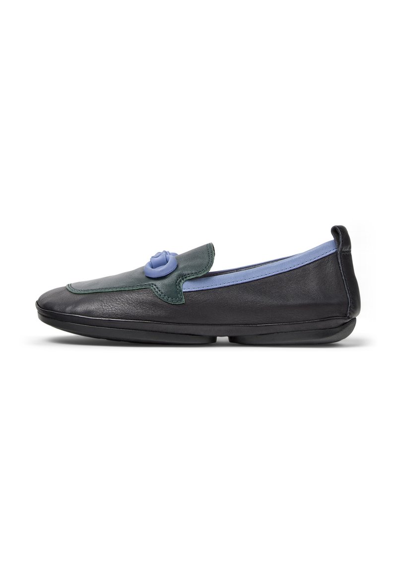 Stylischer schwarzer Slipper mit einer grünen und hellblauen Paneel sowie einer dekorativen blauen Rose auf dem Blatt, vor einem weißen Hintergrund.