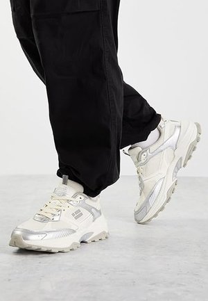 Zapatillas ligeras en blanco y plateado, con un upper de tejido texturizado y suela de goma, cierre de cordones y cuello acolchado.