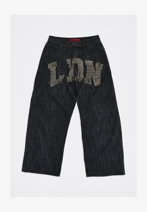 Melnas plataudzītas džinsa bikses ar metāla nagliņām, kas priekšējā daļā veido burtus "LDN", un sarkanu uzlīmi jostas iekšpusē.