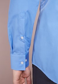 Lichtblauw lange mouwen shirt met knoopmanchetten, een gladde textuur en een getailleerde pasvorm, met twee knopen op de manchetten en een licht gebogen zoom.