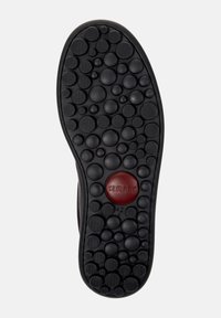 Suola di scarpa nera con motivi circolari testurizzati e un logo circolare rosso etichettato "Camper" con la taglia "42" visibile.